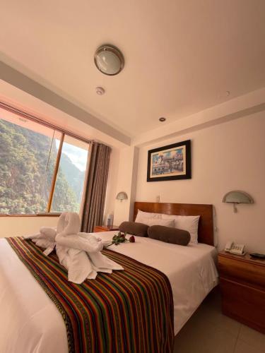 a bedroom with a bed with white sheets and a window at Flower's House MachuPicchu in Machu Picchu