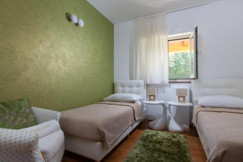 a room with two beds and a couch and a window at Villa Diora in Karojba