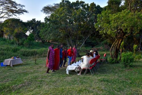 a group of people standing around a table in a field at Mara Chui Eco-Resort in Sekenani