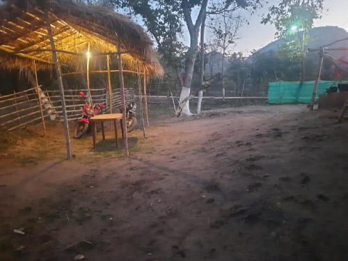 a motorcycle parked in front of a hut with a table at PALASH Pahar Resort in Jhalida