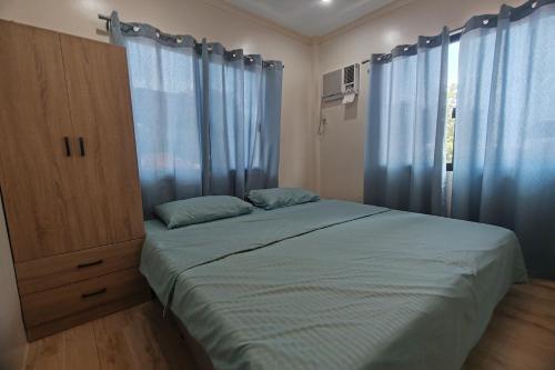 a bedroom with a bed with blue curtains and a cabinet at Intoy's Place Panglao near Beach in Panglao