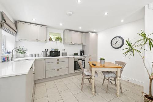 a kitchen with white cabinets and a table and chairs at Flower Cottage by Ludlow Castle with Onsite Parking in Ludlow