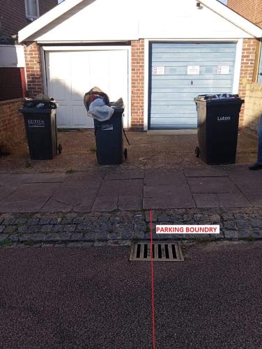 a parking boundary sign in front of two trash cans at Ensuite Near Luton Station in Luton