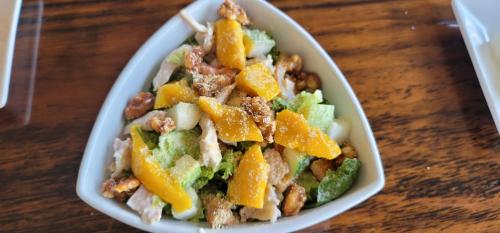 a salad in a white bowl on a wooden table at Sempre Premier Inn - MACTAN AIRPORT HOTEL in Mactan