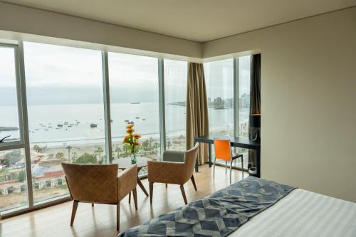 a bedroom with a bed and a desk and chairs at Hotel Terrado Cavancha in Iquique