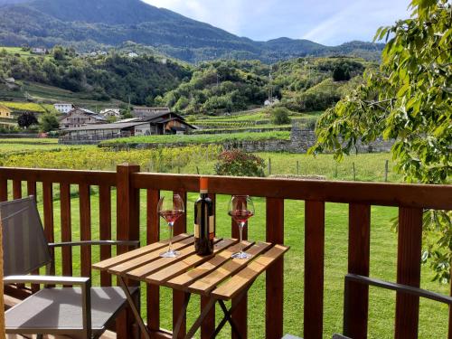 a wooden table with two glasses of wine on a balcony at La Vigne de Papagran in Aosta