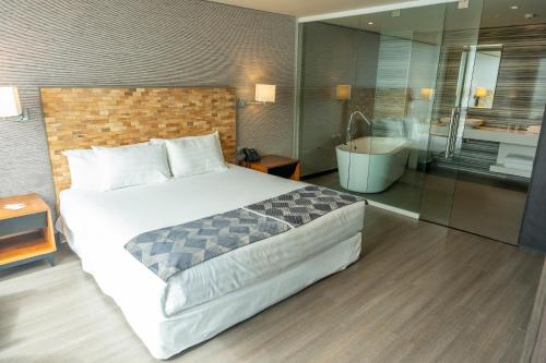 a bedroom with a large bed and a bathroom at Hotel Terrado Cavancha in Iquique