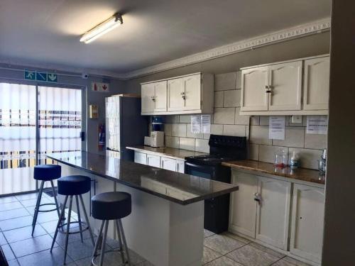 a kitchen with white cabinets and bar stools at Brix 7 single beds in Johannesburg
