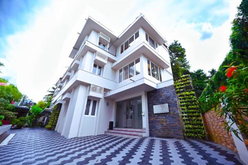 a white house with a cobblestone driveway at Castilo Inn Hotel Apartments in Cochin