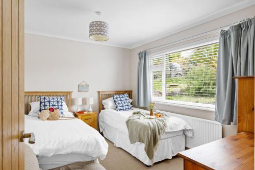 Un dormitorio con dos camas y una ventana. en 15 Churchfields - Bungalow with Estuary Views and Parking, en Dartmouth