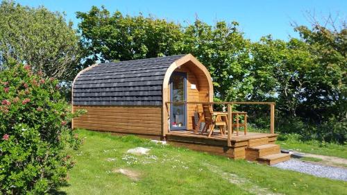 a small wooden cabin with a table on the grass at Sea and Mountain Luxury Glamping Pods in Holyhead