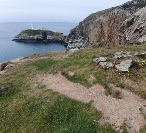 an island in the ocean with a lighthouse on it at Sea and Mountain Luxury Glamping Pods in Holyhead