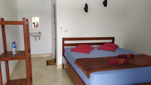 a bedroom with a bed with red pillows and a sink at Olala Bungalows and Restaurant in Sabong