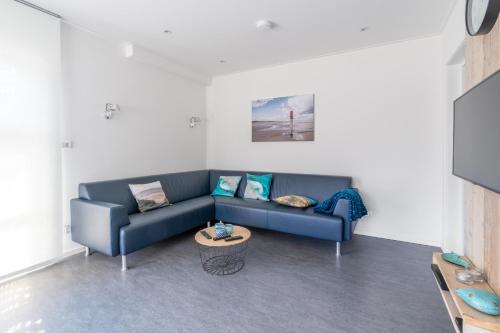 a living room with a blue couch and a table at Epelaan 34 in De Koog