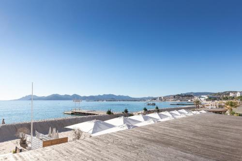 - une rangée de chaises longues blanches sur une plage dans l'établissement Suite Sandra - Appartement de luxe, à Cannes