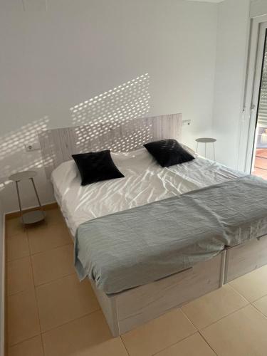 a bedroom with a bed with white sheets and black pillows at Casa Golf Mar Menor in Los Martínez
