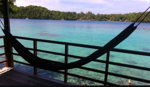 a hammock on a porch with a view of the water at Olala Bungalows and Restaurant in Sabong