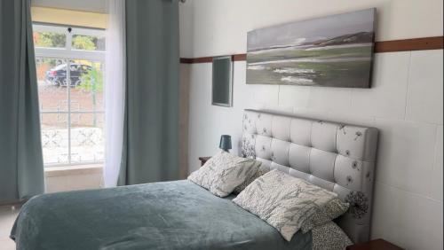 a bedroom with a bed with a headboard and a window at Sweet Home - Praia das Rocas in Castanheira de Pêra