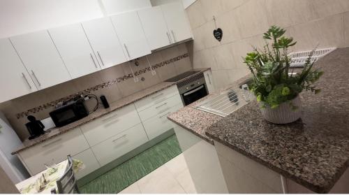 a kitchen with white cabinets and a vase of flowers on a counter at Sweet Home - Praia das Rocas in Castanheira de Pêra
