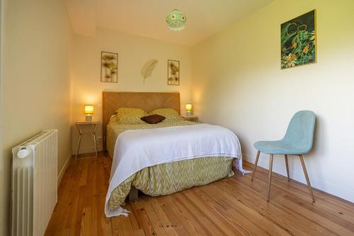 une chambre avec un lit et une chaise bleue dans l'établissement La fermette d'Emilienne, à Le Val-Saint-Père