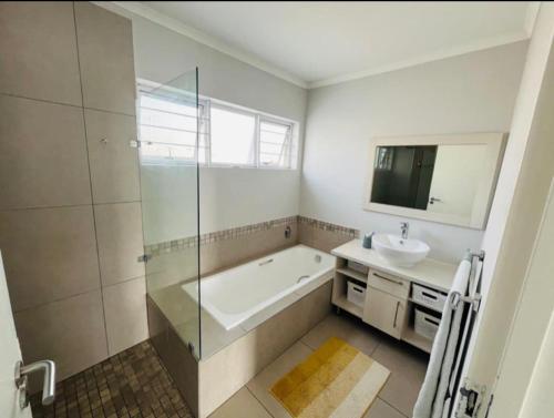 a bathroom with a shower and a tub and a sink at Ore Private property in Midrand