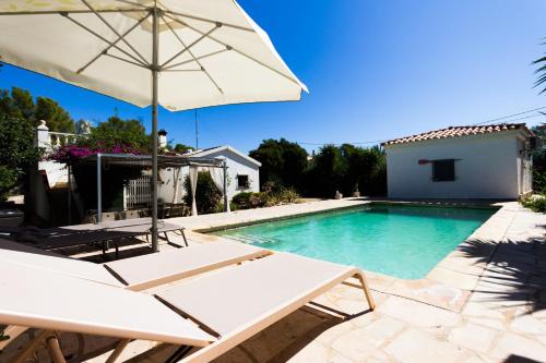 a swimming pool with an umbrella and chairs and a table and an umbrella at INNOUTHOME Chalet familiar con piscina privada numero u in L'Ametlla de Mar