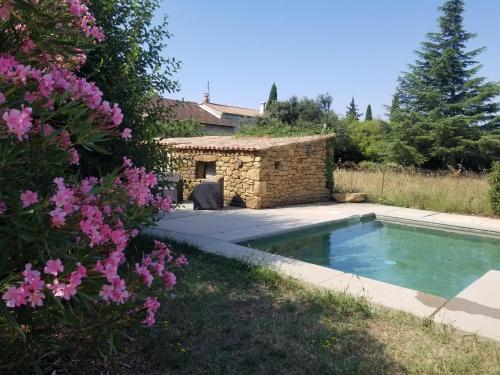 une piscine dans un jardin avec des fleurs roses dans l'établissement Rose Antique, à Valréas