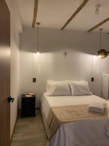 a bedroom with a white bed and a night stand at Casaboutiquemariajose in Guadalupe