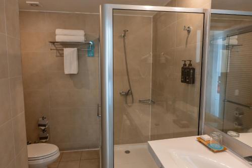 a bathroom with a shower and a toilet and a sink at Terrado Suites Iquique in Iquique