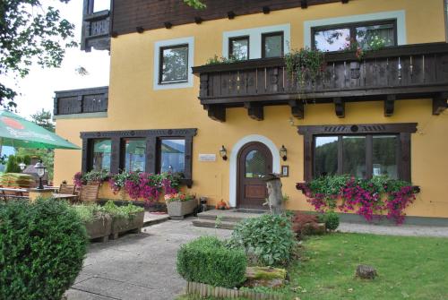 una casa amarilla con flores a un lado. en Pension Savisalo, en Ramsau am Dachstein
