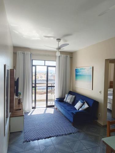 a living room with a blue couch and a sliding glass door at Cabo Frio apartamento Casa Mar in Cabo Frio