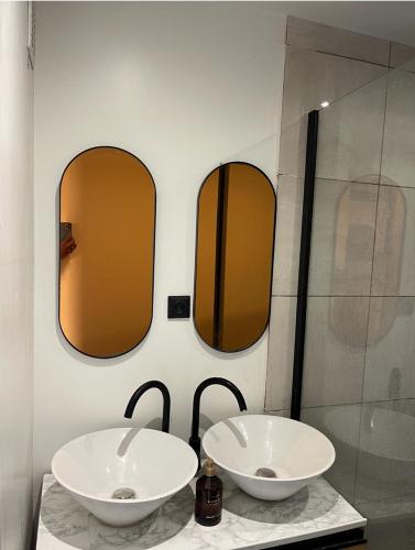 deux lavabos dans une salle de bain avec deux miroirs dans l'établissement Rahou, à Étampes