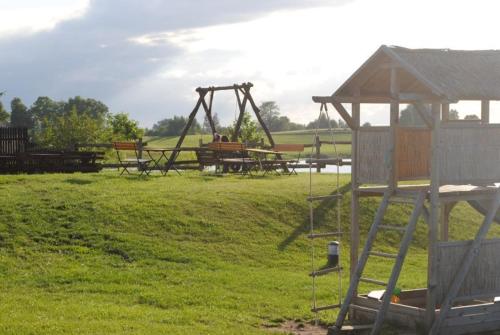 a group of picnic tables in a field with a playground at Karczma Stary Młyn in Giżycko