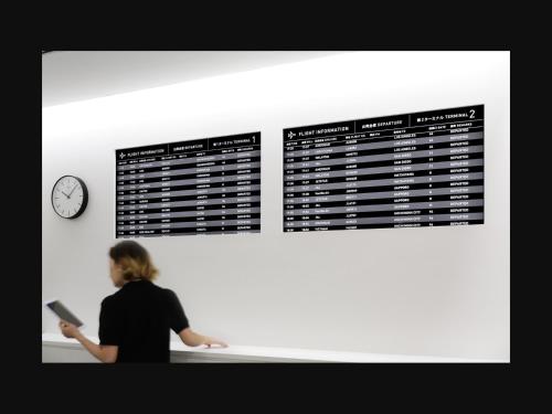 a woman standing in front of a wall with a clock at 9h nine hours Narita Airport in Narita