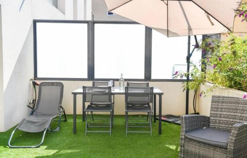 - une table et des chaises dans une pièce avec pelouse dans l'établissement Superbe appartement avec Terrasse, piscine & Parking Privé à Marseille, à Marseille