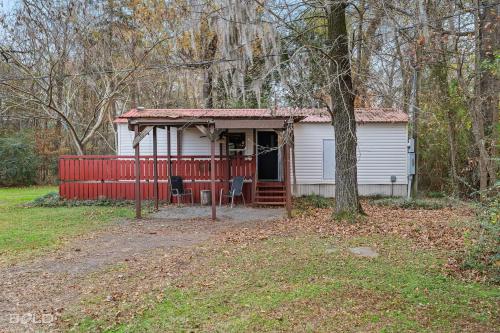 a small house with a red fence in a yard at Chic Cypress View Cabin Wkayaks & Canoes in Karnack
