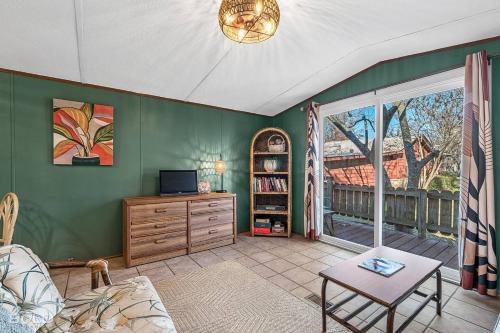 a living room with green walls and a table and a tv at Chic Cypress View Cabin Wkayaks & Canoes in Karnack