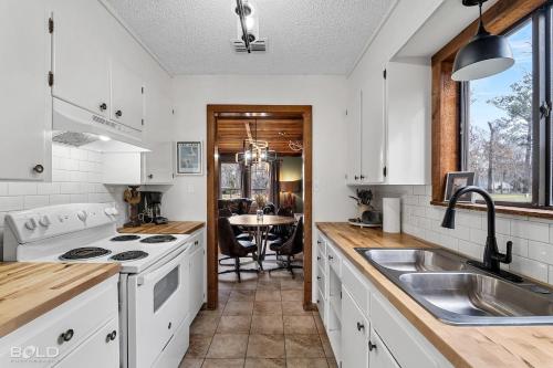 a kitchen with white cabinets and a sink and a table at Cool Moss Stone Lodge Wkayaks & Canoes in Karnack