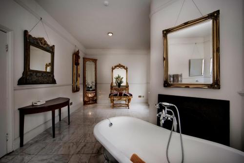 a bathroom with a tub and a table and mirror at Stone Court House in Maidstone