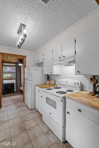 a kitchen with white appliances and a tile floor at Cool Moss Stone Lodge Wkayaks & Canoes in Karnack