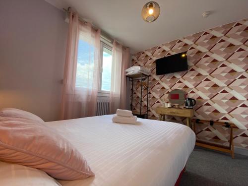a bedroom with a white bed and a tv on a wall at Hôtel du Musée in Granville