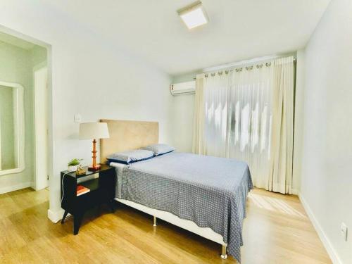 a white bedroom with a bed and a window at Apto Aconchegante em Floripa in Florianópolis