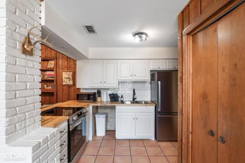 a kitchen with white cabinets and a brick wall at Cedar Wood Lodge Wkayaks & Canoes, Outdoor Dining in Karnack