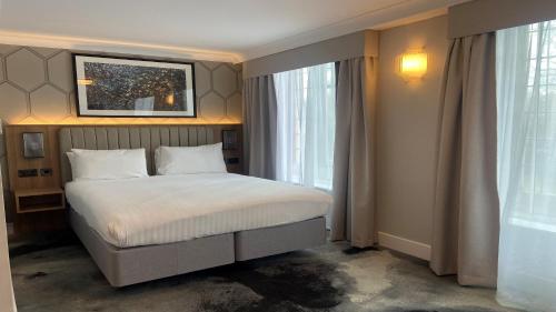 a bedroom with a bed and a large window at London Chigwell Prince Regent Hotel, BW Signature Collection in London