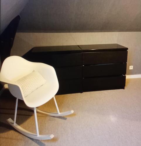 une chaise blanche assise devant une commode noire dans l'établissement Agréable appartement derriere les arenes de Nimes, à Nîmes