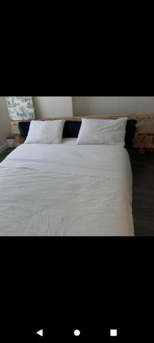 - un lit avec des draps et des oreillers blancs dans l'établissement Agréable appartement derriere les arenes de Nimes, à Nîmes