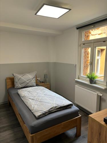 a bedroom with a bed and a window at Ferienwohnung H&M Immobilien Querfurt 2 in Querfurt