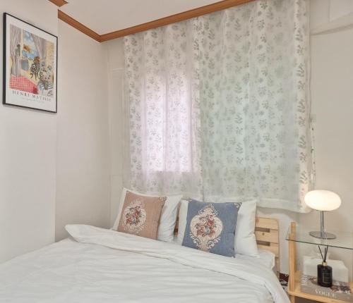 Un dormitorio con una cama blanca y una ventana. en Happy Home Stay, en Seúl