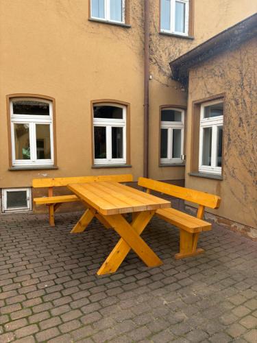 a picnic table and bench in front of a building at Ferienwohnung H&M Immobilien Querfurt 2 in Querfurt