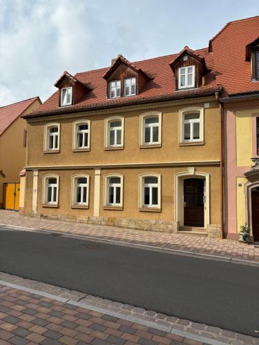 a yellow building with white windows on a street at Ferienwohnung H&M Immobilien Querfurt 2 in Querfurt